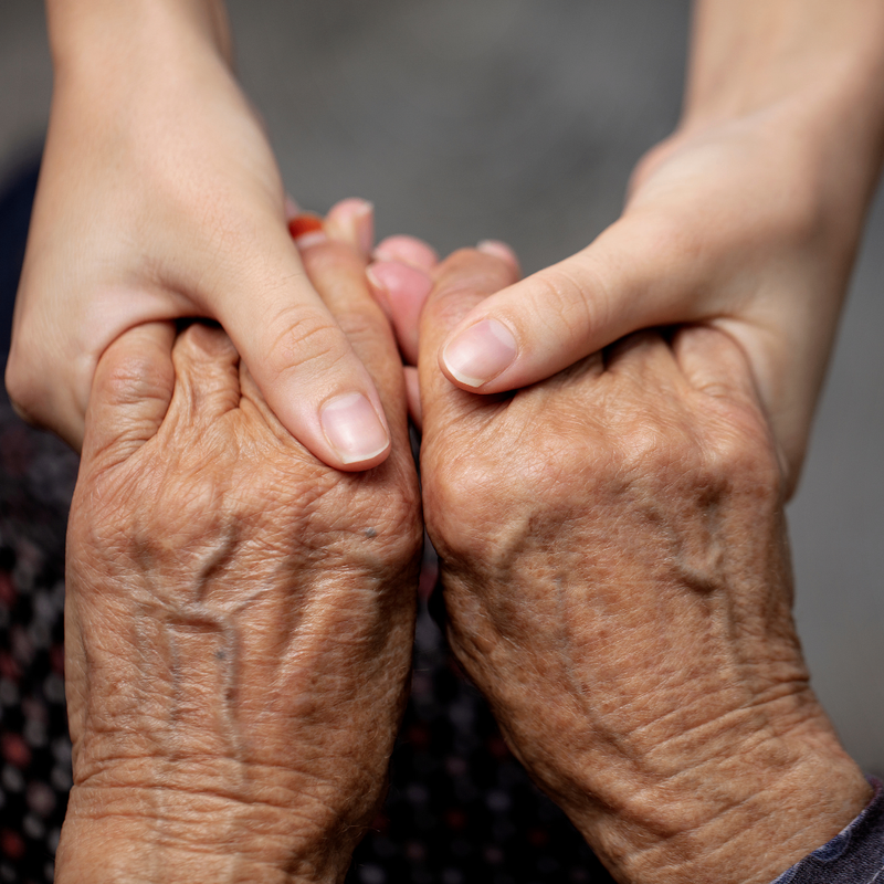 Young hands holding an older person's hand - how to talk about personal care with a loved one