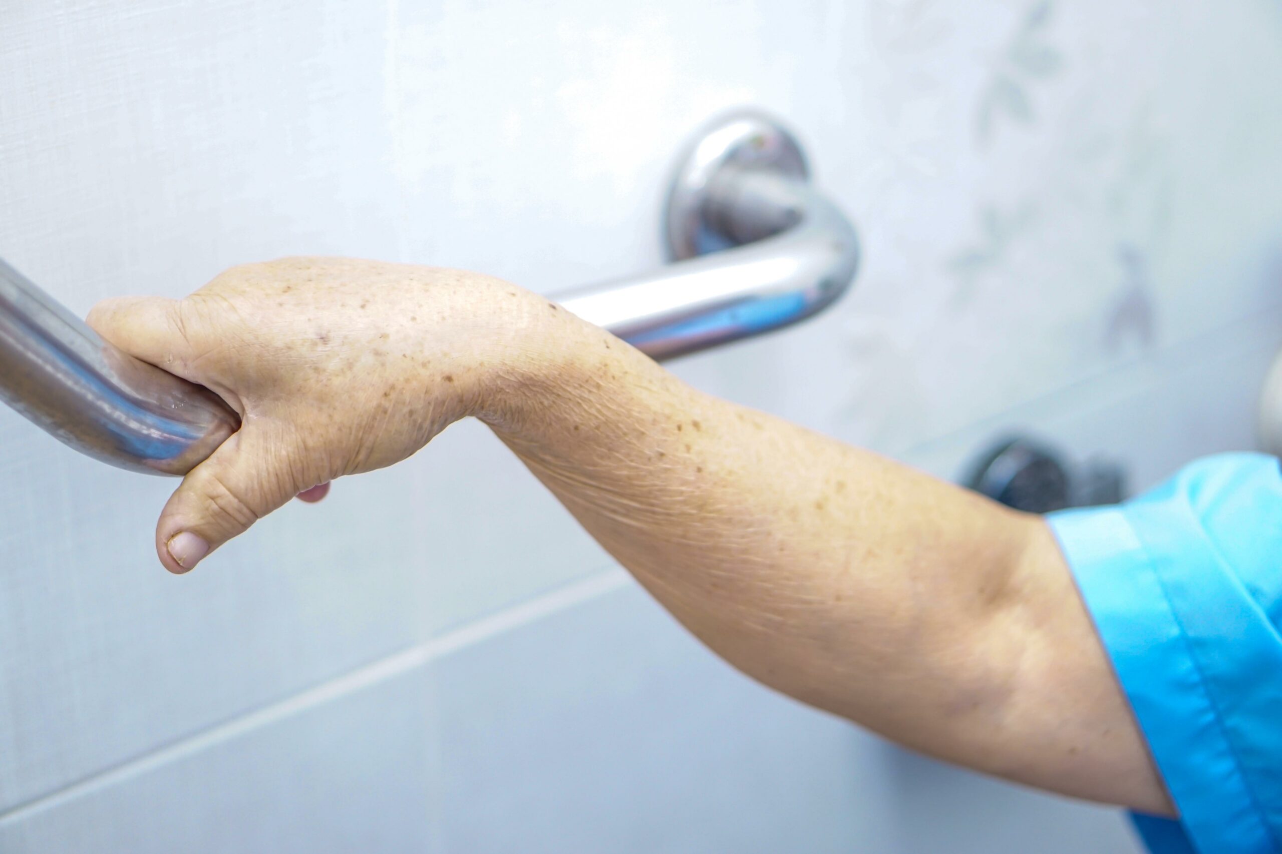 An elderly person holding a handrail representing bathroom safety