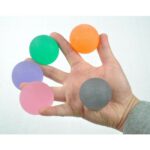 A hand, in between each finder is Able2 Gel Therapy Balls