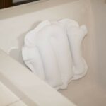 The Atlantis Bath Pillow on the side of a bath.