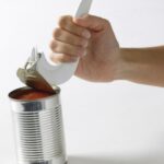 A hand using the Can Key (J-popper) White on a can. On a white background.
