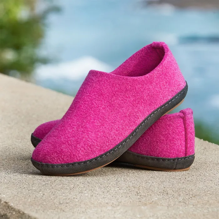 A pair of Cosyfeet Mooch in Damson Wool sitting on a wall with a river blurred in the background. The pair of shoes has one on top of each other.