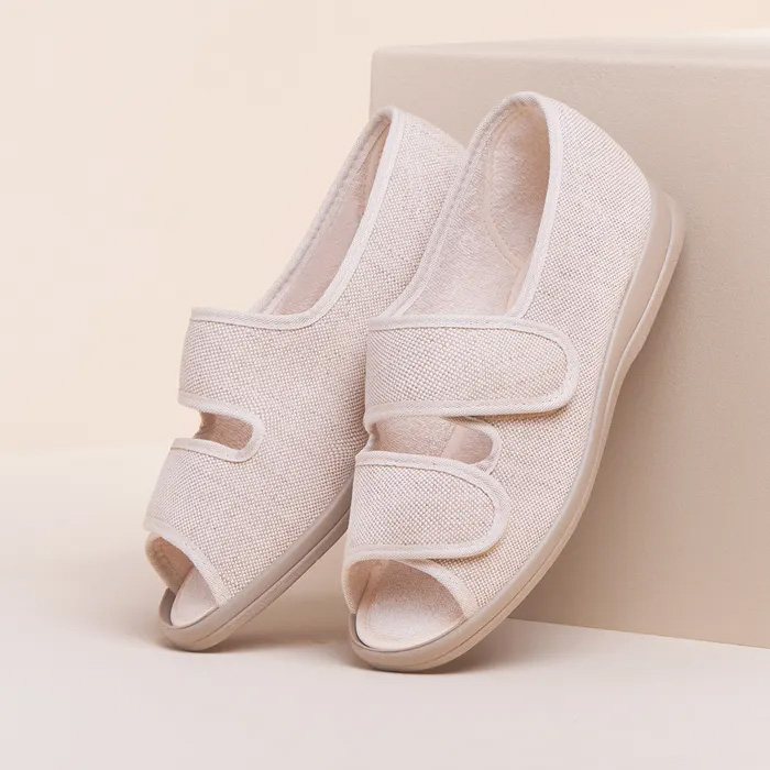 A pair of Cosyfeet in Beige sitting upright leaning on a box of similar colour, the background of similar colour.