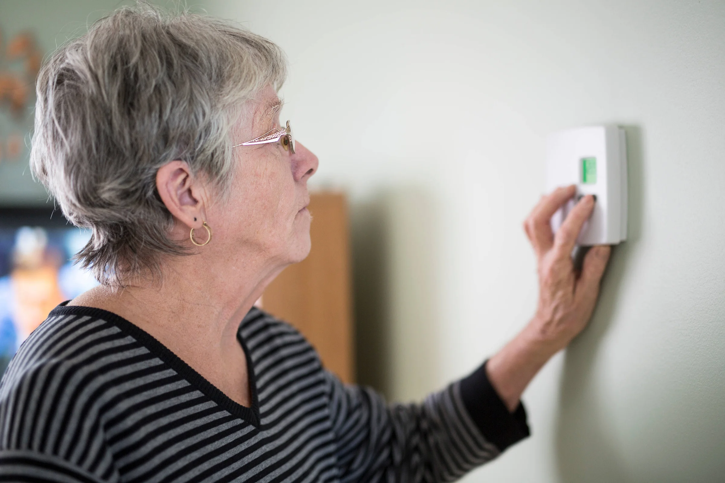Fuel Payments Cuts: Lady turning her thermostat down