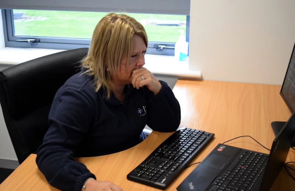 Premier Community Careers: Nicola Cope sat at her desk on her computer