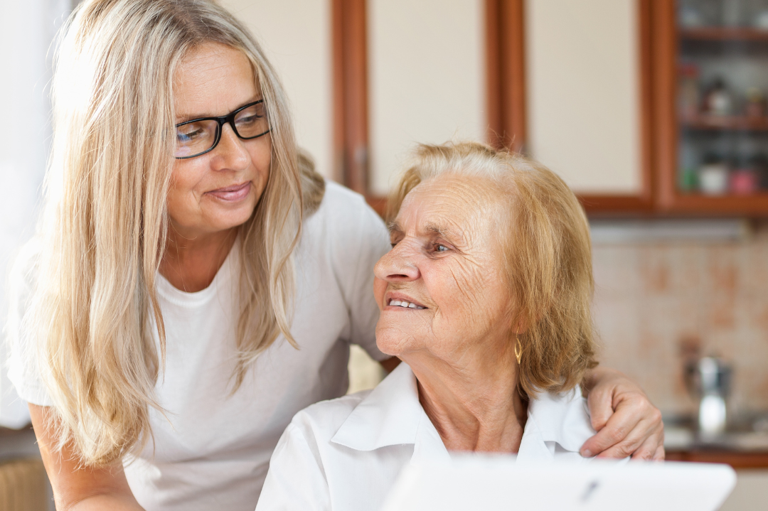 Daughter with her elderly mum looking on a tablet for more information on arranging home care