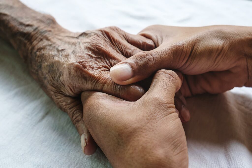 Palliative and End-of-Life Care Support: Younger person holding an older person's hand.