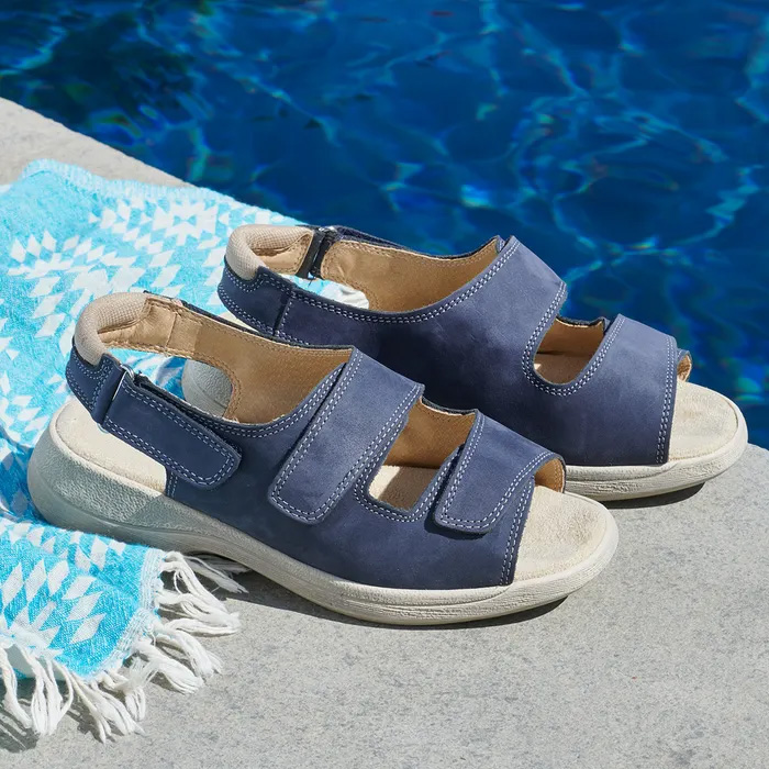 A pair of Cosyfeet Sunny Sapphire Blue sitting on a blue and white beach towel, next to a summer pool.