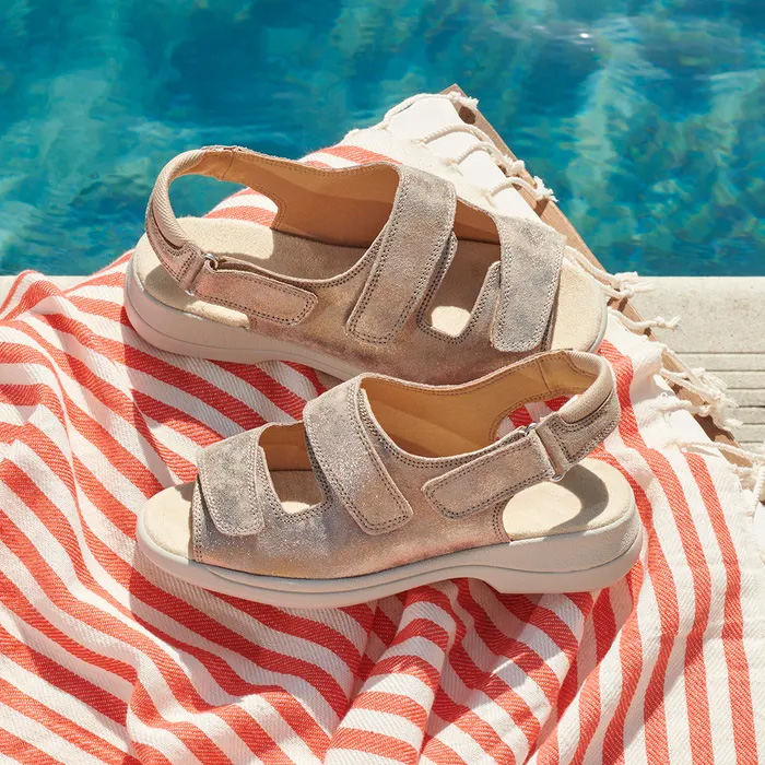 Cosyfeet Sunny Gold Shimmer sitting on a red and white striped beach towel, next to a summer pool.