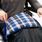 Drive Padded Leg Cosy sitting on a user in a wheelchair on a white background.