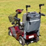 Splash Crutch/Walking Stick Bags Grey on a mobility scooter sitting on a grassy field.