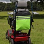 Splash Crutch/Walking Stick Bags Hi-vis on a mobility scooter sitting on a grassy field.
