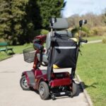 Splash Crutch/Walking Stick Bags Black sitting on a path between to patches of grass in a park like environment.