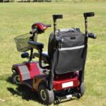 Splash Crutch/Walking Stick Bags Black on a mobility scooter sitting on a grassy field.