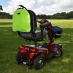Splash Slipover Scooter Bag Hi-Vis on a mobility scooter sitting on a grassy field.