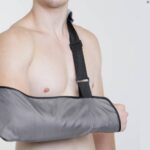 A topless man wearing the Kedley Orthopaedic Supports Fabric Arm Pouch