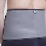 Kedley Pro-Light Neoprene Back Support around a models waist on a white background.