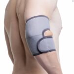 A topless male model wearing the Kedley Pro-Light Neoprene Elbow Support on a white background.
