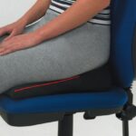 A woman sitting on a Harley Designer Wedge on a chair on a white background.