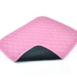 Vida Washable Chair Pads in Pink turned up on one corner, underneath a black colour, sitting on a white background.
