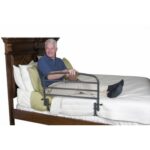 A man in a bed holding onto the Stander 30 Safety Bed Rail