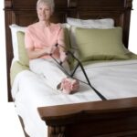 A woman sitting on a bed holding the Stander Bed Caddie.