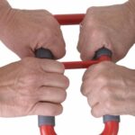 Two sets of hands holding onto the soft grey sections on the Stander Handy Handle Held in Red.