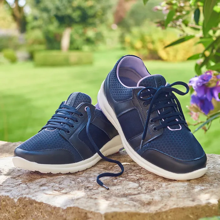 A pair of Cosyfeet Viva Navy Lilac sitting on a stone wall overlooking a green garden.