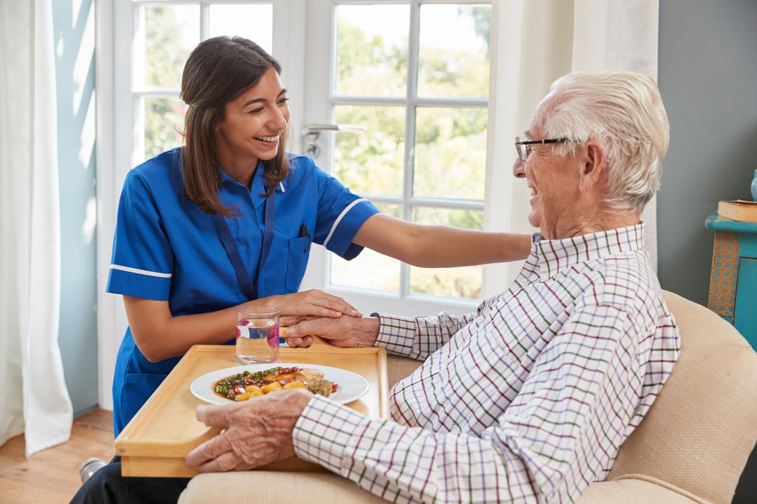 Domiciliary Care Worker assisting elderly gentleman with his breakfast