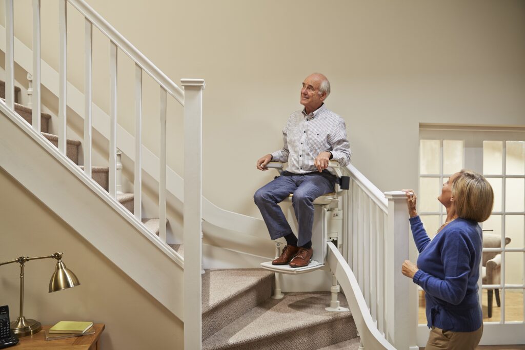 Elderly man sat on his stairlift whilst elderly woman watches