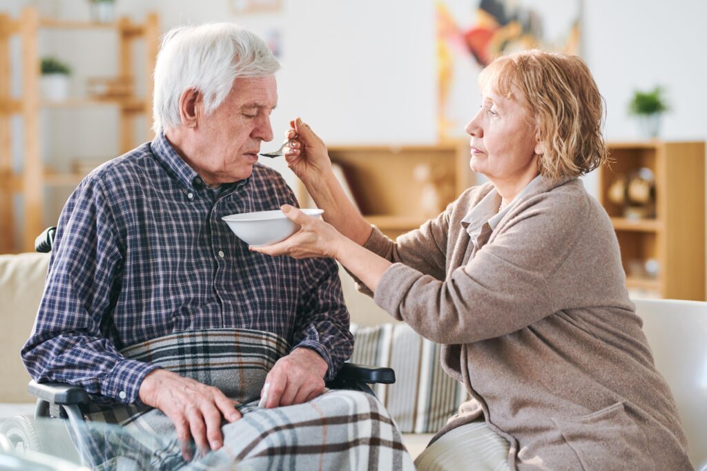 A woman looking after her husband by feeding him representing unpaid carers in derbyshire