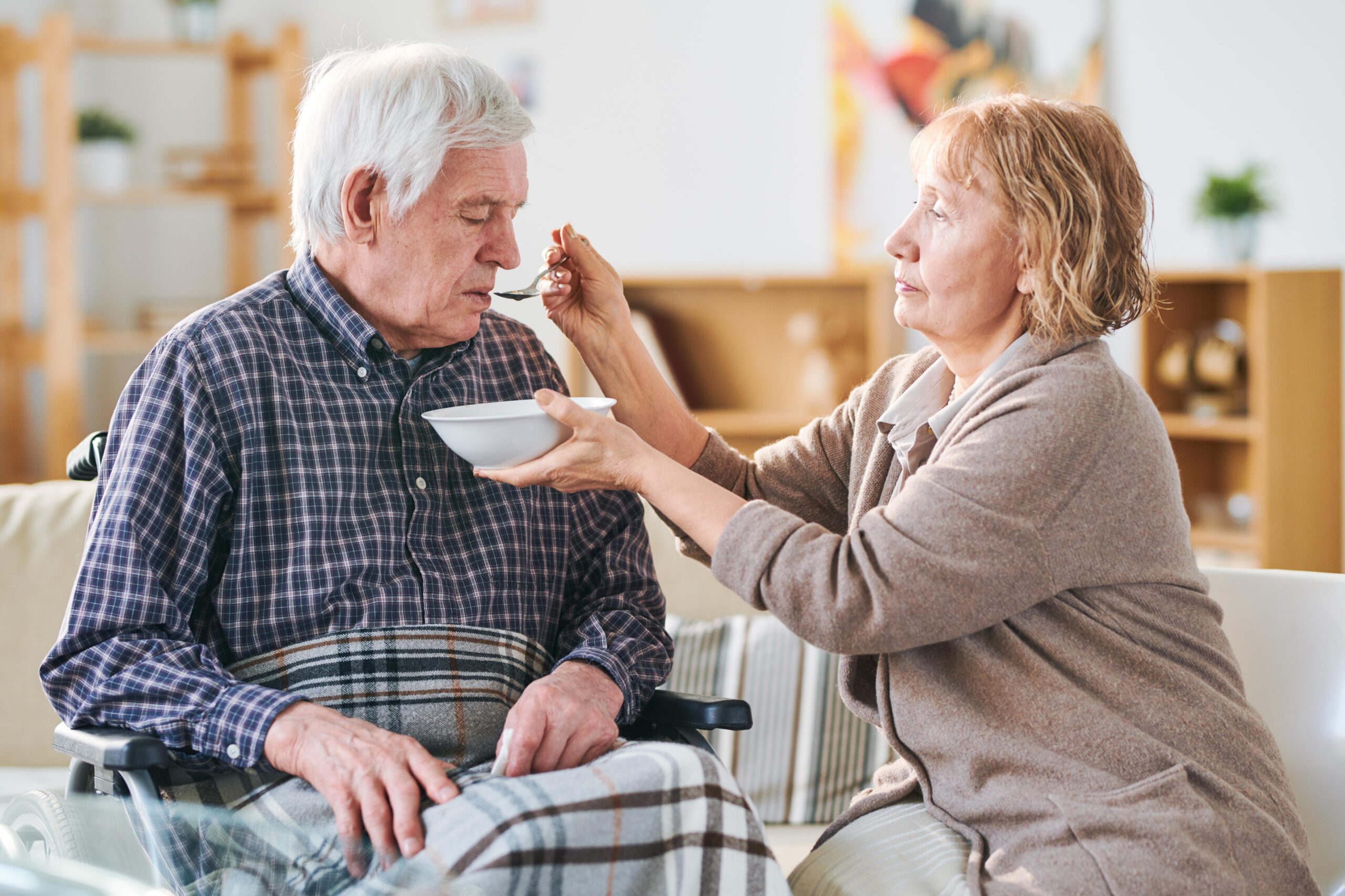 A woman looking after her husband by feeding him representing unpaid carers in derbyshire