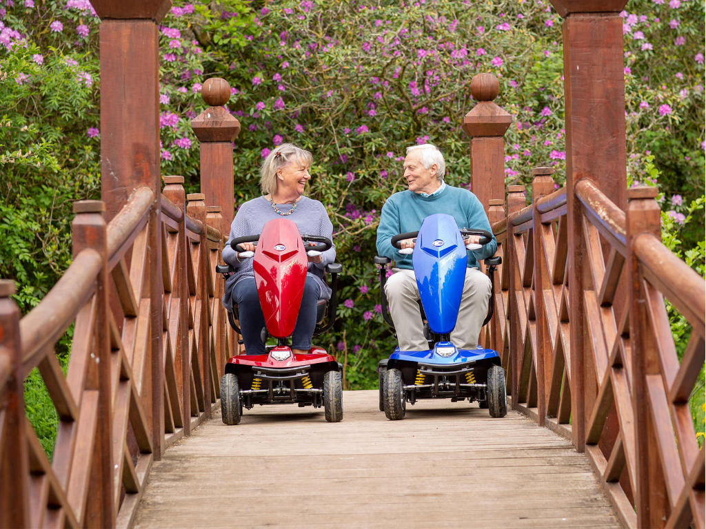 two elderly adults driving their mobility scooters