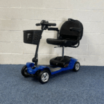 Pride Apex Lite - Blue sitting on a blue carpet and white brick wall.