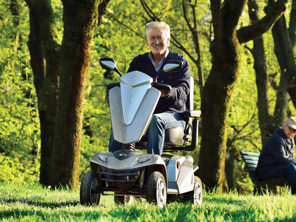 man driving mobility scooter through the woods