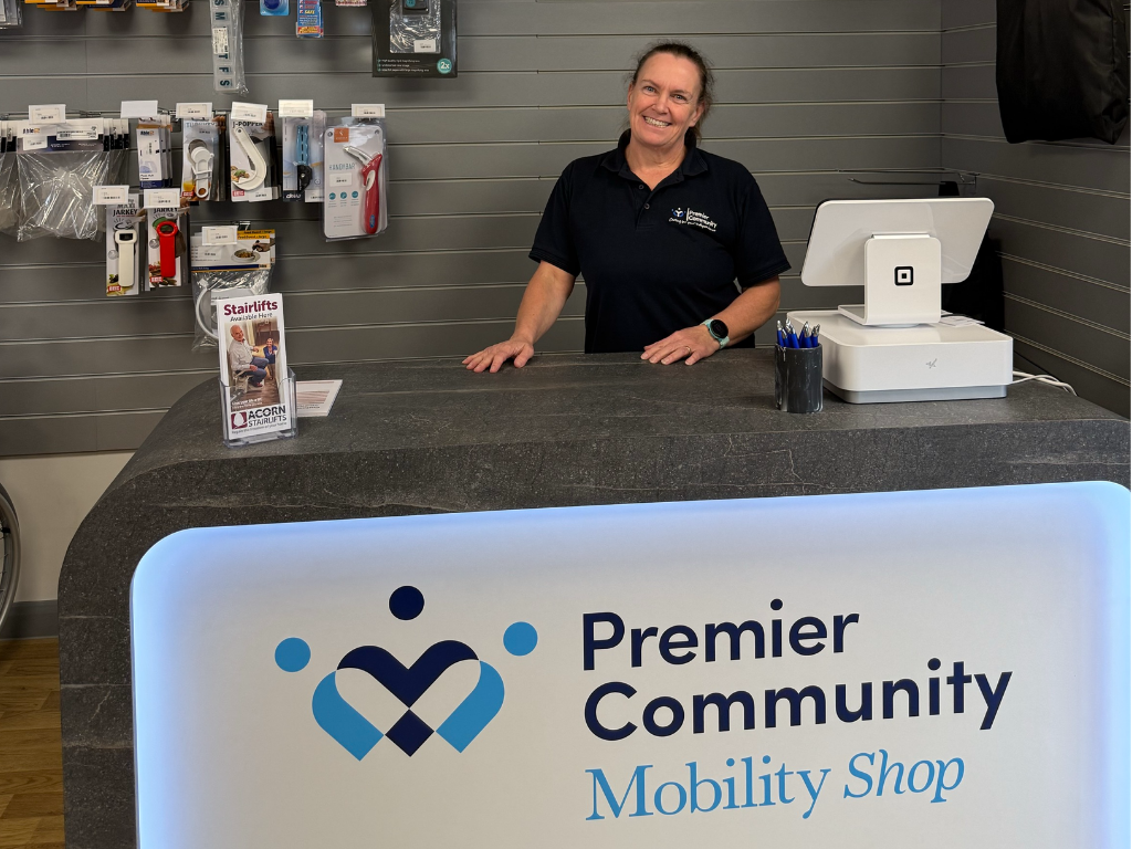 Paula smiling looking at the camera positioned behind the Premier Community Mobility desk
