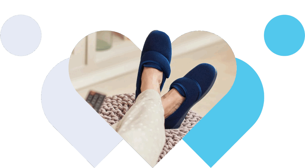 A pair of cosyfeet slippers on someone's feet, crossed over relaxed.