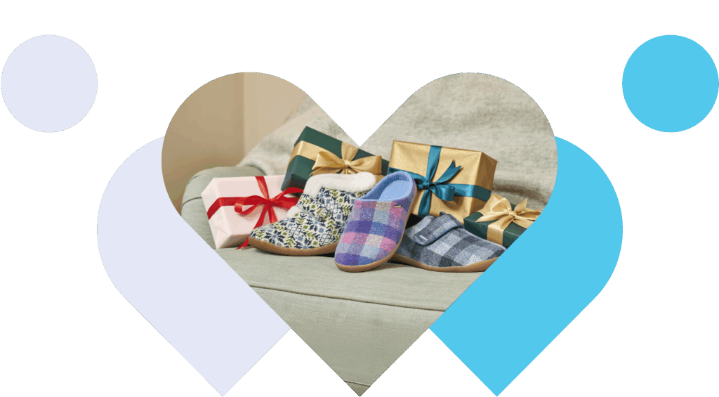 Heart-shaped frame shows Cosyfeet slippers and wrapped gifts on a couch, evoking warmth and festive cheer. Soft colors and ribbons highlight a holiday mood.