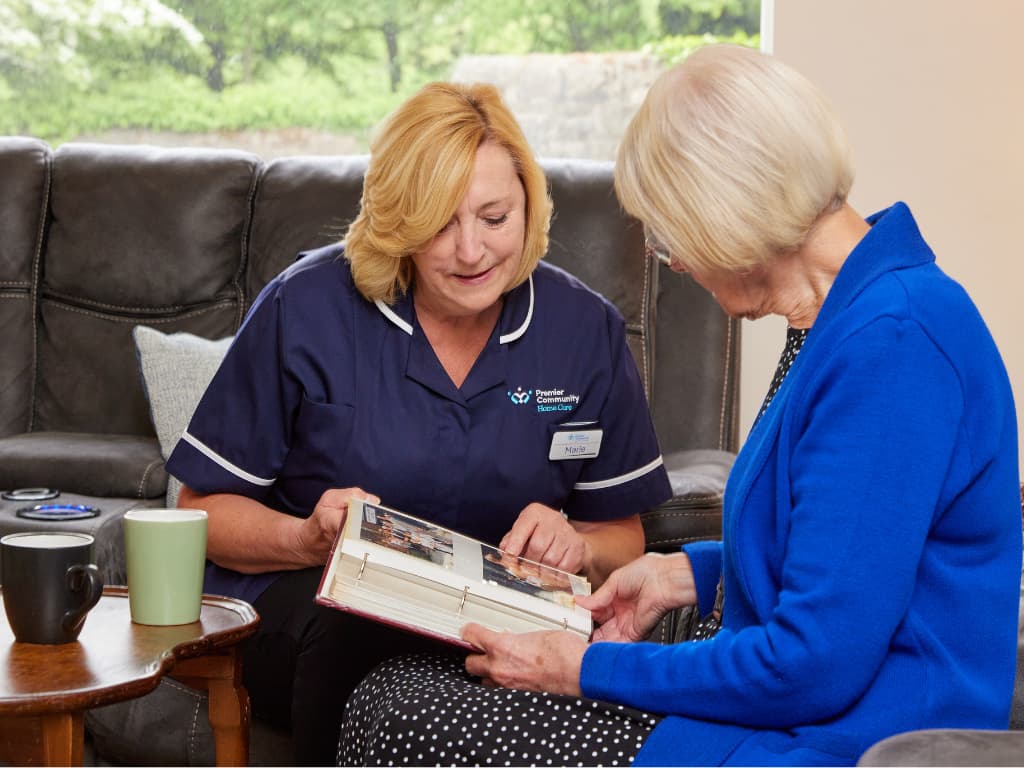 Premier Community Carer looking at a photo album with a service user