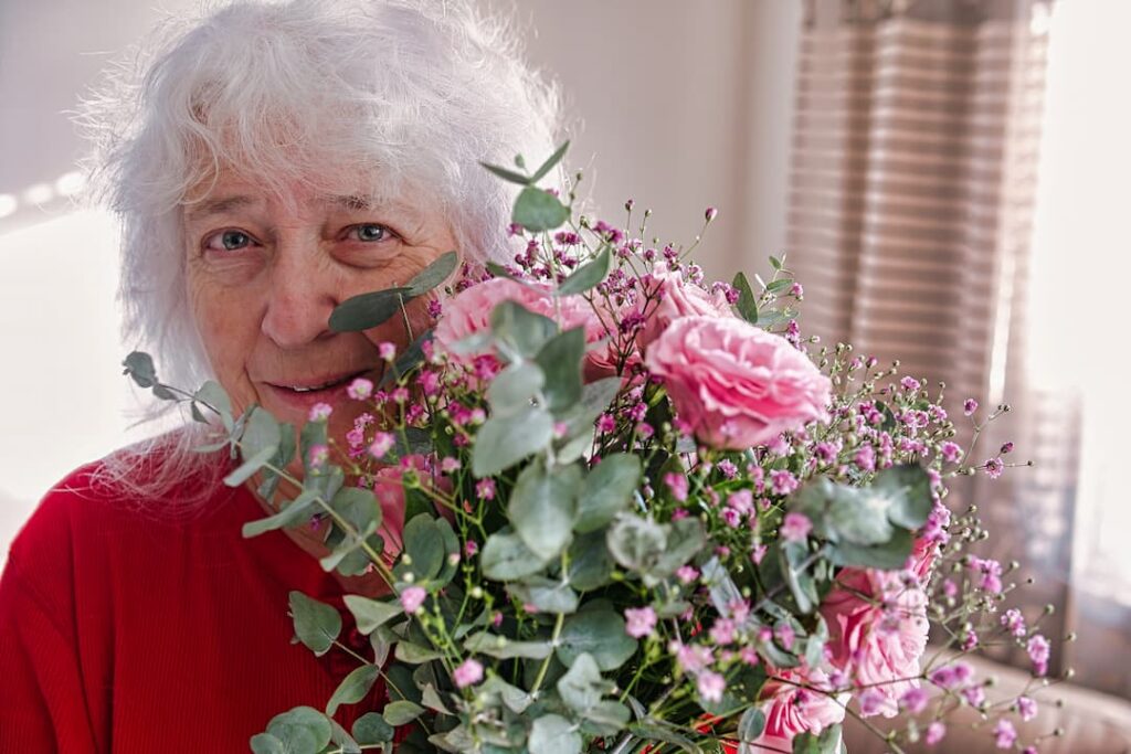 Elder;y client with flowers used as an example of a moment shared in a day in the life of a live-in carer