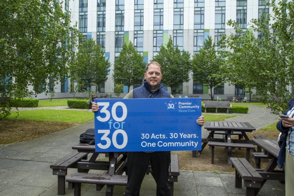 Premier Community's CEO holding a large banner advertising the company's 30for30 campaign.