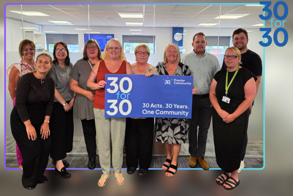 A group of people gathered around a banner that states 30for30, 30 years, 30 acts. one community.