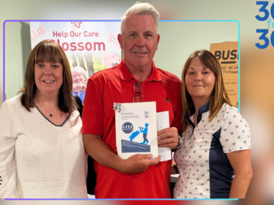 3 people stood together holding a donation image,